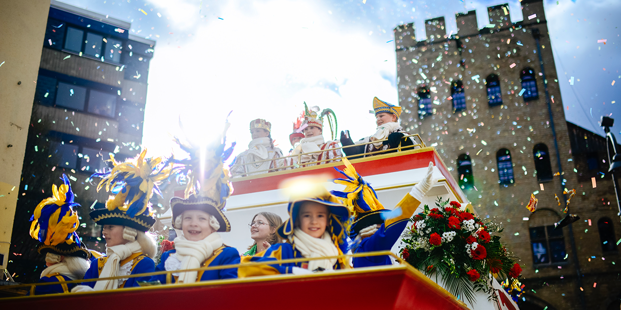 Das Kinderdreigestirn blickt von einem Wagen in die Kamera